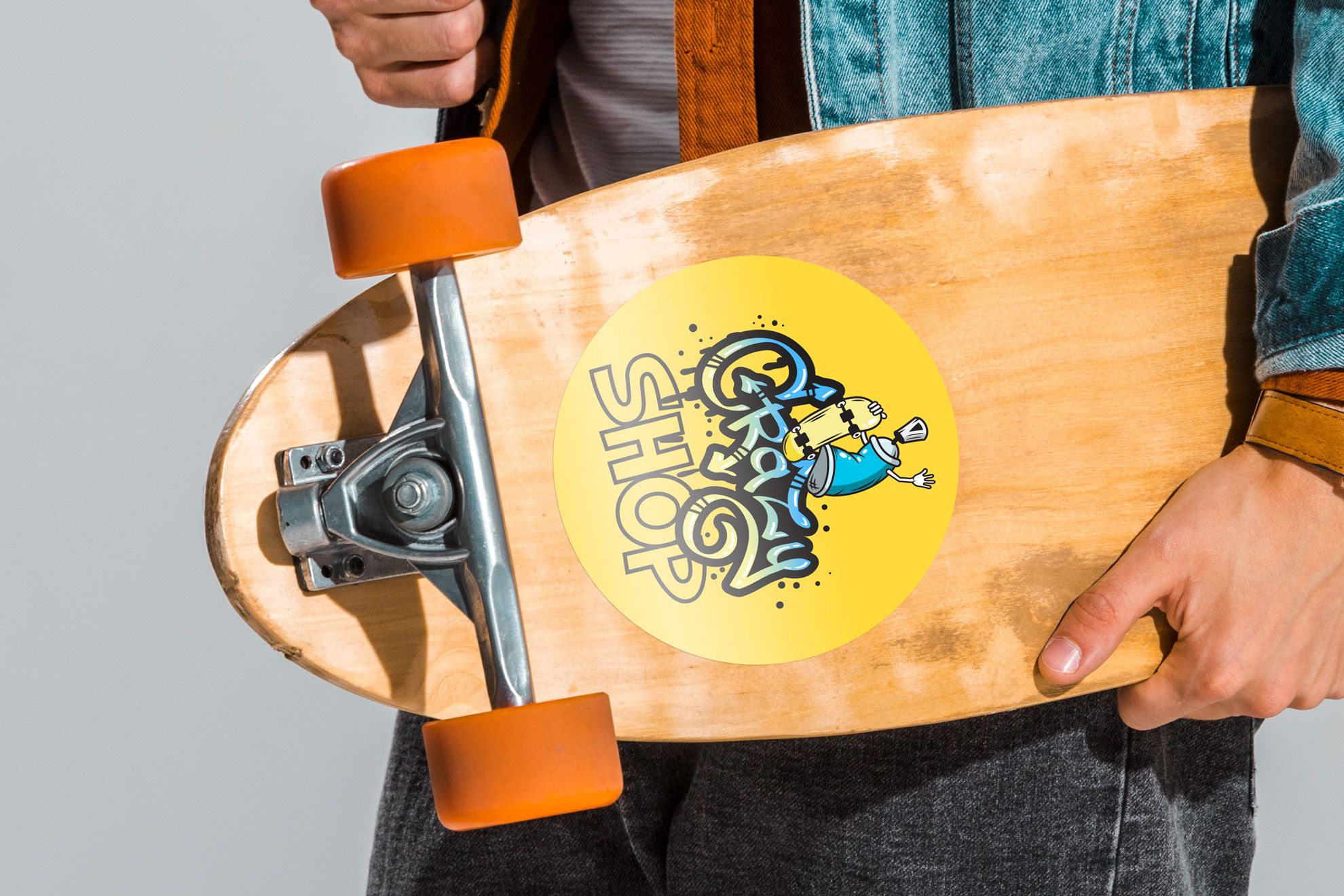 Adesivo rotondo giallo vivace con design personalizzato applicato a una tavola skateboard in legno. Questi duraturi adesivi rotondi personalizzati sono ideali per personalizzare skateboard, laptop, bagagli e prodotti promozionali. Progetta e stampa i tuoi adesivi di qualità premium online con il nostro servizio di stampa conveniente.