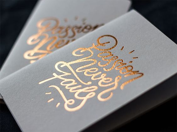 Due biglietti da visita grigi con calligrafia in oro rosa con scritta 'Passion Never Fails' — un design elegante in stile calligrafico con finiture decorative. I biglietti da visita con doratura a caldo in calligrafia e carta pastello sono ideali per coach, creativi, fotografi e brand lifestyle che desiderano una carta premium tattile e distintiva.