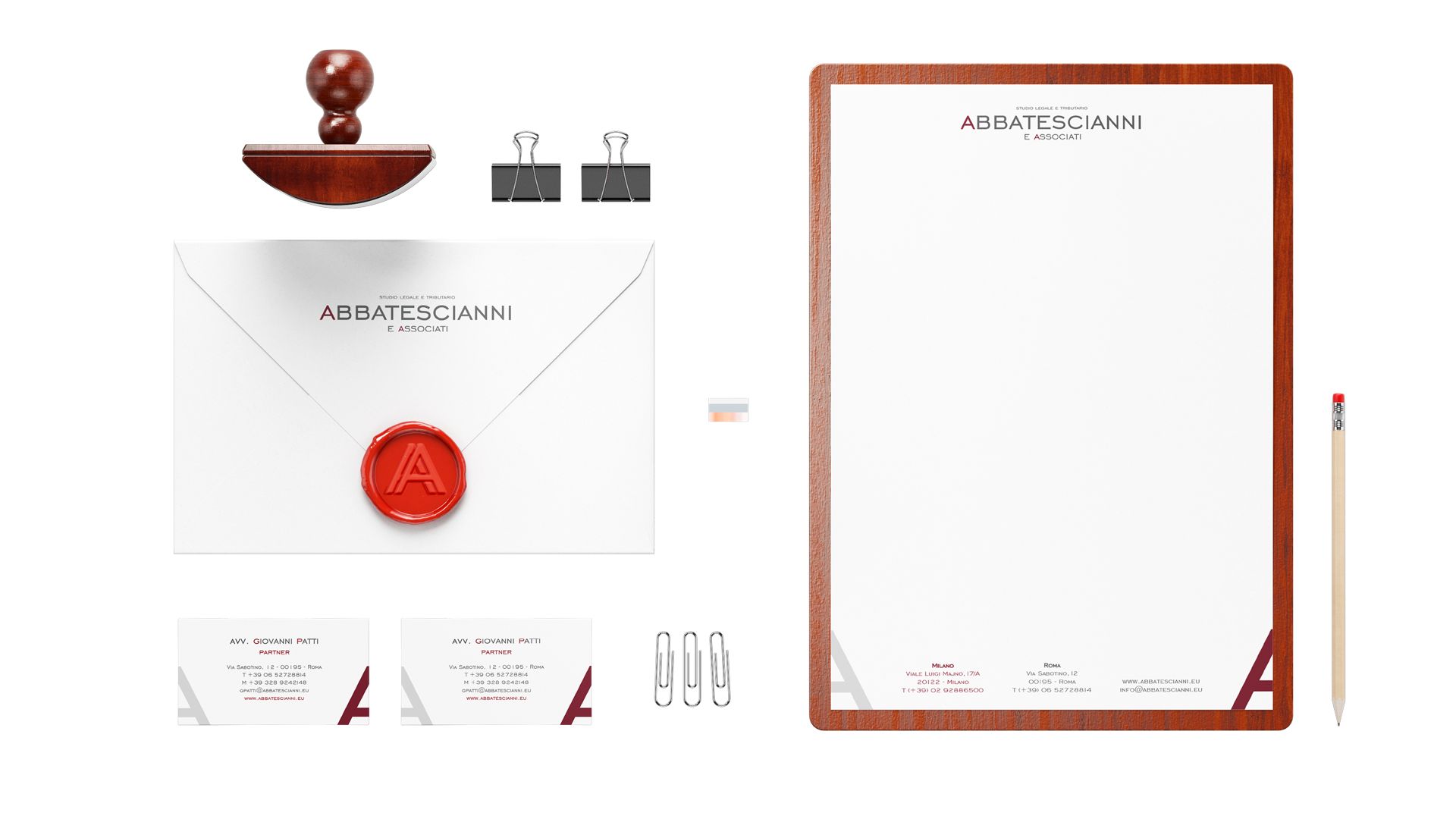 Kit di cancelleria completo per lo studio legale Abbatescianni con biglietti da visita, carta intestata, busta con ceralacca rossa, timbro e fermagli. Il design professionale utilizza accenti in legno scuro e sigillo in ceralacca. Esempio di realizzazione grafica professionale per identità aziendale e cancelleria stampata.