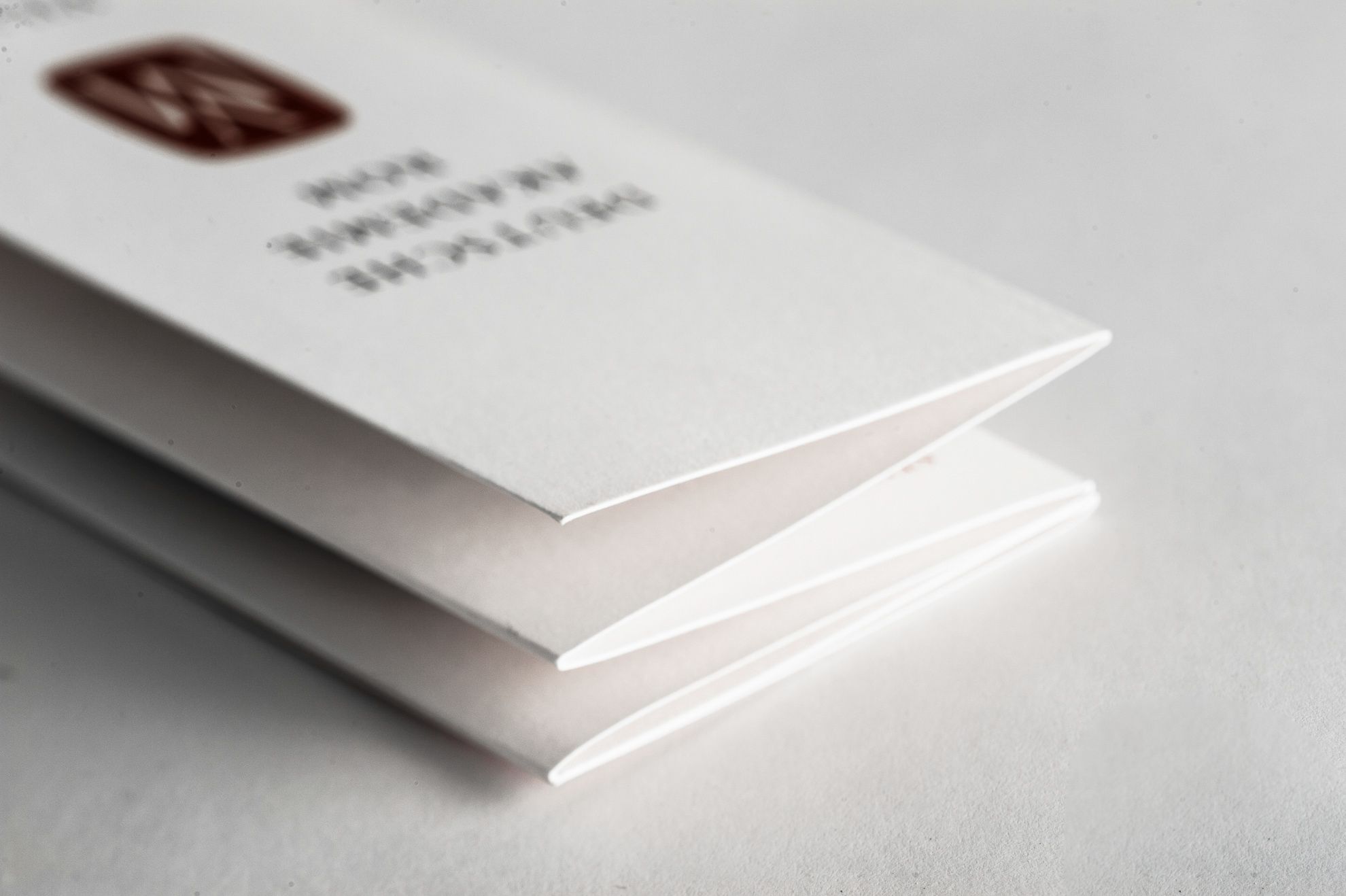 Pieghevoli grigie impilate per Accademia Tedesca con stampa Pantone bordeaux e nero su carta Kriocolor grigia premium 170 gr. Le pieghe a soffietto visibili mostrano la precisione delle tecniche di cordonatura e piega a soffietto. Un eccellente esempio della qualità di stampa pieghevole disponibile attraverso il nostro servizio di preventivo.