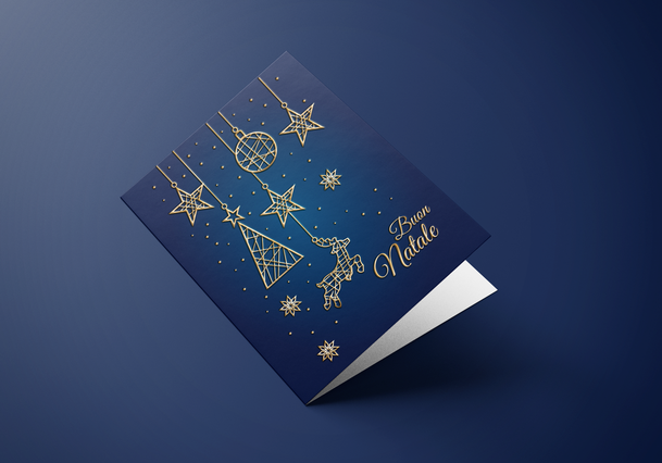 Un biglietto di Natale pieghevole con copertina blu navy profondo e ornamenti natalizi geometrici in oro — stelle appese, palline, fiocchi di neve e abete triangolare — con lettering oro 'Buon Natale'. I biglietti di Natale personalizzati con oro colato su carta navy premium creano un'impressione natalizia elegante e memorabile per aziende e professionisti.