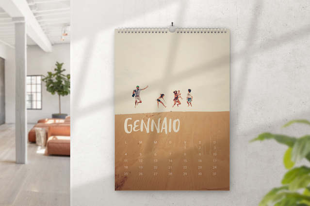 Un calendario da muro a spirale con foto appeso a una parete bianca luminosa che mostra gennaio con una calda scena desertica in seppia, silhouette di famiglia in cammino e nome del mese in lettering a mano. I calendari da muro fotografici personalizzati sono il regalo perfetto per famigliari e amici — stampati su carta fotografica, ordinabili anche in una sola copia.