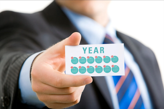 Un compatto calendario tascabile presentato nella mano di un professionista, che mostra il design portatile ideale per portafogli e uso quotidiano. Con un layout bianco pulito e elementi di tracciamento blu, questo calendario tascabile plastificato combina funzionalità e aspetto professionale. Il servizio di stampa online di Sprint24 ti consente di personalizzare i calendari tascabili in grandi q…