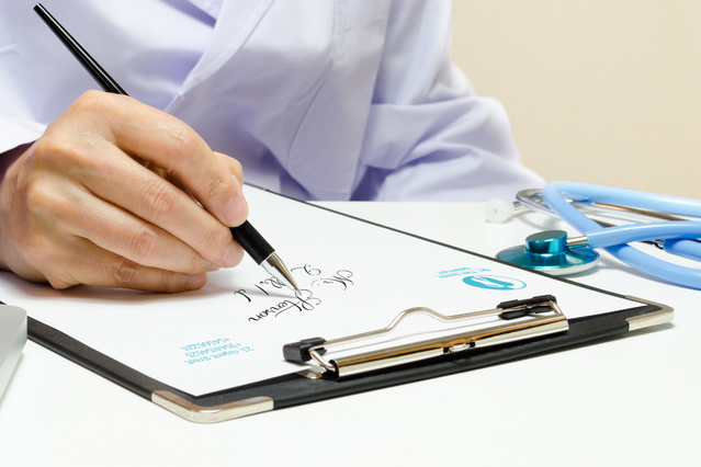 Carta intestata professionale che mostra un medico che scrive su clipboard con stetoscopio visibile. Fogli di qualità premium personalizzabili progettati per medici, studi medici e professionisti sanitari. Ordina la tua carta intestata medico personalizzata online con Sprint24.