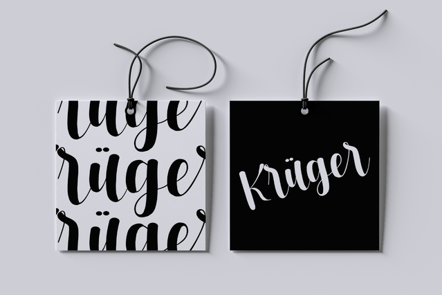 Due cartellini quadrati per abbigliamento del brand Kruger mostrati affiancati: uno bianco con lettere nere in grassetto e uno nero con logo bianco in corsivo. Entrambi i cartellini sono infilati con un cordoncino nero. Perfetto esempio di cartellini sagomati personalizzati per marchi di moda.
