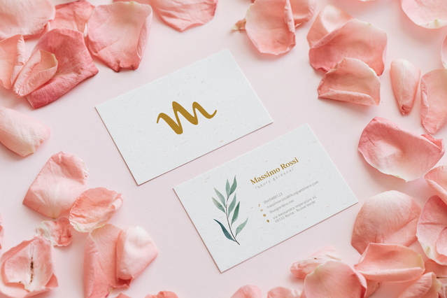 Eleganti biglietti da visita giardiniere bianchi logo M oro ramo. Due eleganti biglietti bianchi logo M oro e ramo botanico Massimo Rossi tra petali di rosa. Sprint24.