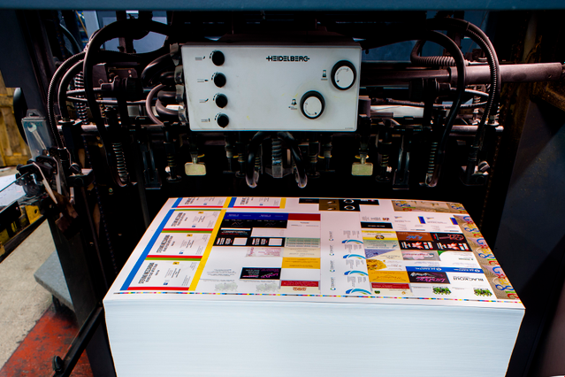 Macchina tipografica offset professionale produce grandi fogli laminati 70x100 cm con stampa 4 colori su carta patinata opaca 400 gr. Plastificazione opaca e verniciatura UV a rilievo garantiscono durabilità e qualità premium per ordini bulking grande volume.