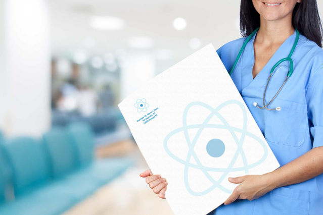 Un'infermiera sorridente in divisa blu che tiene una grande busta bianca per referti medici con logo atomo blu in un corridoio ospedaliero luminoso. Sprint24 stampa buste a sacco per referti personalizzate per studi medici, cliniche e ospedali — ideali per consegnare esami e radiografie in modo professionale.