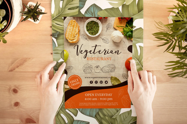 Due mani che aprono un volantino ecologico 'Vegetarian Restaurant' con fotografia di cibo fresco su tavolo in legno circondato da piante tropicali. Sprint24 stampa volantini e cartoline ecologiche su carta naturale o riciclata — ideali per ristoranti vegetariani e brand eco-sostenibili.