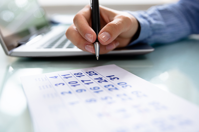 Mano che scrive in un planner personalizzato con penna blu Professionista che usa planner personalizzato per organizzare compiti e scadenze. Sprint24.