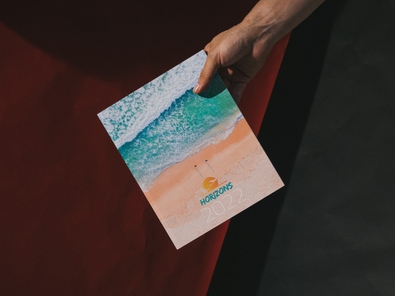 Mano con agenda filorefe Horizons copertina foto mare turchese e spiaggia aerea. 128 pagine Sprint24.