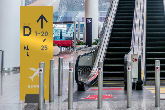 Pannello autoportante di segnaletica direzionale giallo brillante con frecce chiare e display di informazioni alfanumeriche per ambienti di trasporto moderni. Questo pannello totem piuma ultraleggero combina le capacità di segnaletica direzionale professionale con una struttura di base autoportante robusta. Perfetto per aeroporti, stazioni, esposizioni e spazi commerciali che richiedono una comun…