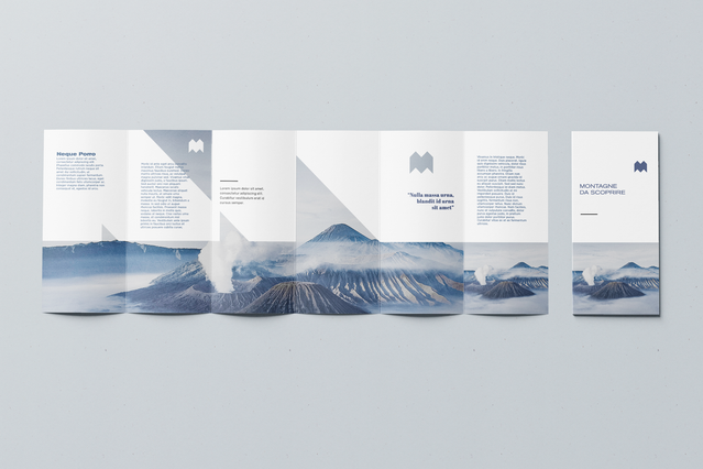 Un pieghevole a 6 ante completamente aperto con layout minimalista bianco che presenta un drammatico panorama di montagna vulcanica blu che si estende sui pannelli centrali, affiancato da colonne di testo pulite e un logo monogramma 'M'. I pieghevoli a 6 ante personalizzati con fotografia paesaggistica a tutta larghezza creano una tela visivamente d'impatto per brand di viaggio e campagne di mark…