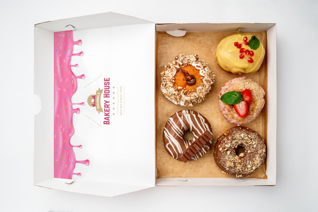 Scatola asporto Bakery House aperta logo rosa interno coperchio e cinque donuts decorati. Sprint24.