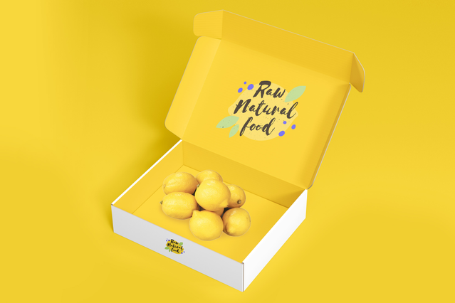 Una scatola automontante gialla e bianca aperta 'Raw Natural Food' con branding lettering scritto a mano sul coperchio interno, riempita di limoni freschi su vivace sfondo giallo. Ideale per brand alimentari, negozi bio ed e-commerce che cercano scatole automontanti personalizzate per packaging che arriva piatto, si assembla istantaneamente e crea un'esperienza di unboxing memorabile.