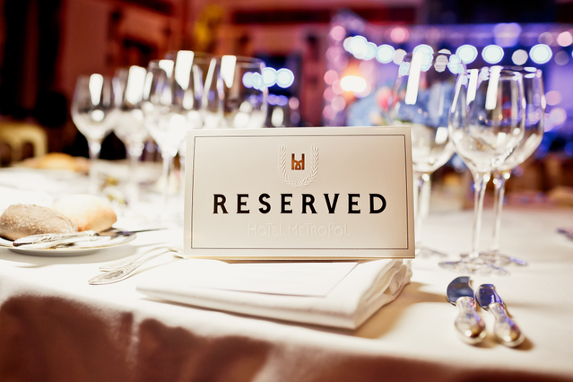 Elegante segnaposto tavolo bianco riservato visualizzato su un tavolo da ristorante formale con tipografia sofisticata e corona decorativa. Perfetto per ristoranti, ristorazione e stabilimenti per contrassegnare i tavoli riservati e migliorare l'atmosfera.